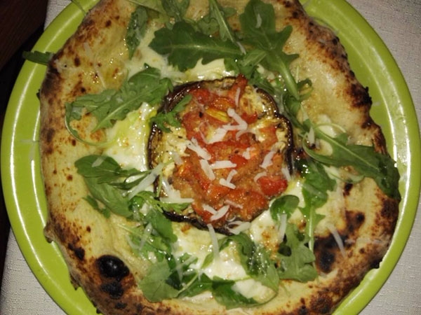 Pizza con melanzana al centro, con pomodorini al forno con base bianca e rucola