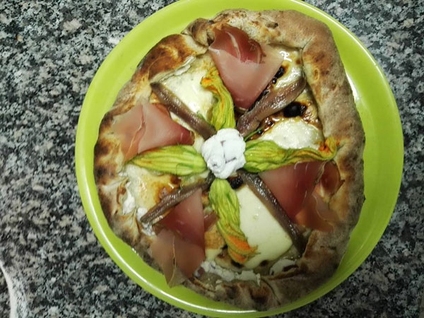 Pizza con fiori di zucchina, speck, alici e ricotta fresca