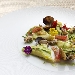 Raviolo di pasta cotta ripieno di ricotta e limone, salsa di zucchine, vongole, gambero rosso e briciole di pane - -