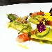 Raviolo di pasta cotta ripieno di ricotta e limone, salsa di zucchine, vongole, gambero rosso e briciole di pane - -